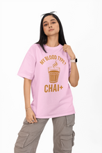 Person wearing a pink t-shirt with 'My Blood Type? Chai+' text and graphic.