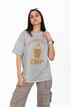 Person wearing a gray t-shirt with 'My Blood Type? Chai+' text and graphic on a white background