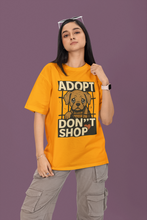 Person wearing a yellow t-shirt with an 'Adopt Don't Shop' graphic on a purple background