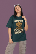 Person wearing a green t-shirt with an 'Adopt Don't Shop' message on a purple background