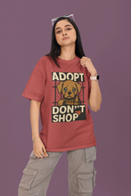 Person wearing a red t-shirt with an 'Adopt Don't Shop' graphic on a purple background