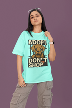 Person wearing a light blue t-shirt with an 'Adopt Don't Shop' graphic on a purple background