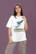 Person wearing a white t-shirt with a graphic and text 'Embrace Transformation' on a purple background